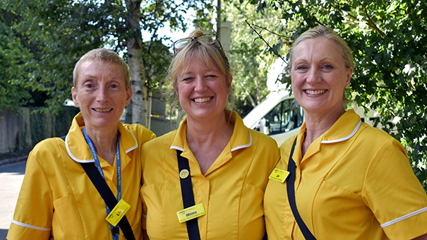 Portrait of the three Family Liaison Facilitators wearing their yellow tunics