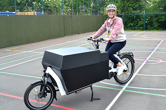 An RUH member of staff sitting on an e-cargo bike