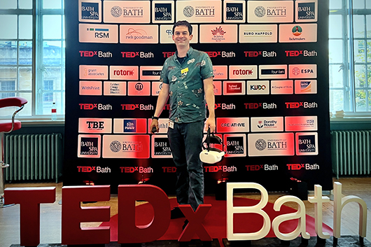 Dr Darren Hart on stage at TEDX Bath holding a VR headset