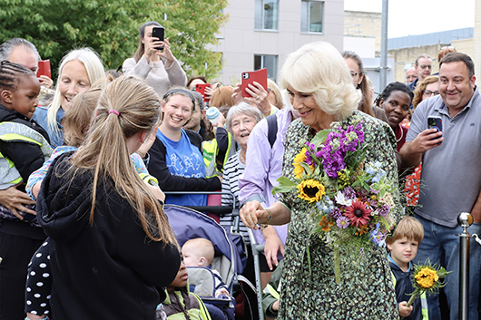 Her Majesty the Queen meeting members of the public outside the Dyson Cancer Centre smiling and holding a bouquet of flowers