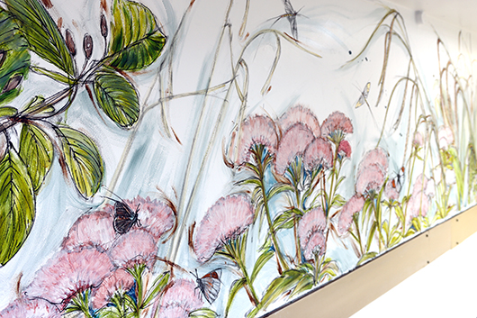 Photograph of the mural on the wall of the diabetes department depicting wildflowers meadow, damselflies and a butterfly on a flower