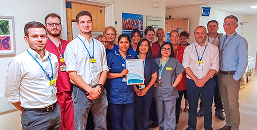 Group photo of the endoscopy team with a member of the team holding up the framed award