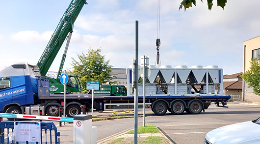 Large-scale heating infrastructure equipment being delivered by crane off the back of a truck