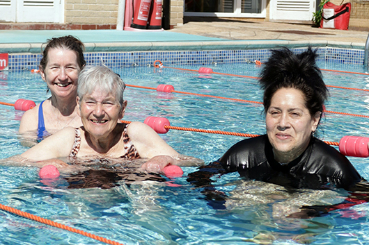 Four stoma patients in the RUH outdoor pool smiling at the camera