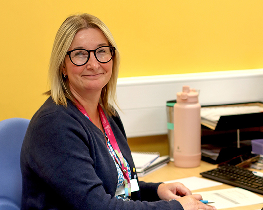 Lead Research Midwife Catherine Bressington sitting at her desk looking towards the camera and smiling