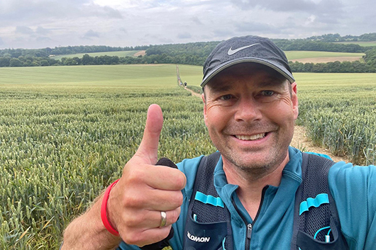 Rob Hart standing in the countryside smiling and giving a thumbs up to the camera
